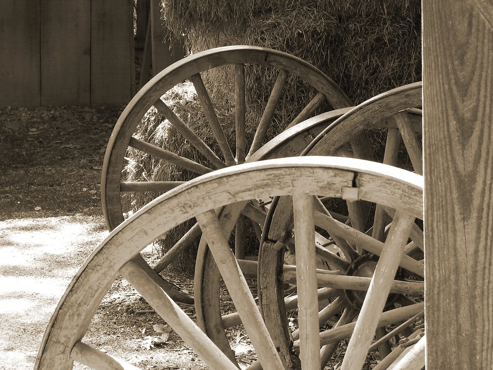  Photo: Black and white picture of wooden wheels and hay in a barn