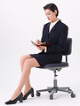 Free Stock Photo: A beautiful woman in a business suit sitting in a chair isolated on a white background.
