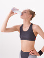 Free Stock Photo: A beautiful blonde drinking a bottle of water isolated on a white background