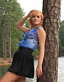 Free Stock Photo: A beautiful young woman posing against a tree by a lake