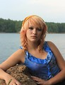 Free Stock Photo: A beautiful young woman posing on a rock by a lake