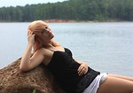 Free Stock Photo: A beautiful young woman posing on a rock by a lake