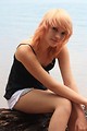 Free Stock Photo: A beautiful young woman posing on a rock by a lake