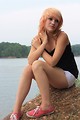 Free Stock Photo: A beautiful young woman posing on a rock by a lake