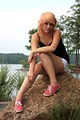 Free Stock Photo: A beautiful young woman posing on a rock by a lake