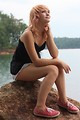 Free Stock Photo: A beautiful young woman posing on a rock by a lake
