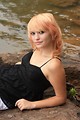 Free Stock Photo: A beautiful young woman posing on a rock by a lake