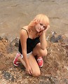 Free Stock Photo: A beautiful young woman posing on rocks by a lake