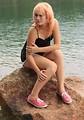 Free Stock Photo: A beautiful young woman posing on a rock by a lake