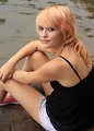 Free Stock Photo: A beautiful young woman posing on a rock by a lake