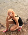 Free Stock Photo: A beautiful young woman posing on rocks by a lake