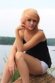 Free Stock Photo: A beautiful young woman posing on a rock by a lake