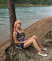 Free Stock Photo: A beautiful young woman posing against a tree by a lake