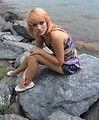 Free Stock Photo: A beautiful young woman posing on a rock by a lake