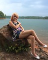 Free Stock Photo: A beautiful young woman posing on a rock by a lake