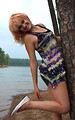 Free Stock Photo: A beautiful young woman posing against a tree by a lake