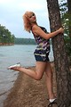 Free Stock Photo: A beautiful young woman posing against a tree by a lake