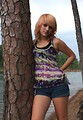 Free Stock Photo: A beautiful young woman posing against a tree by a lake
