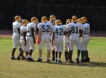 Free Stock Photo: Middle school football players in a huddle on the field.