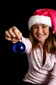 Free Stock Photo: A beautiful young girl in a pink santa hat holding a blue ornament