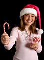 Free Stock Photo: A beautiful young girl in a pink santa hat holding candy canes