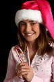 Free Stock Photo: A beautiful young girl in a pink santa hat holding candy canes