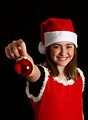 Free Stock Photo: A cute young girl in a Santa hat holding a Christmas ornament