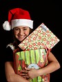 Free Stock Photo: A cute young girl in a Santa hat holding a bag of presents