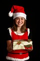 Free Stock Photo: A cute young girl in a Santa hat holding a Christmas present