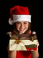 Free Stock Photo: A cute young girl in a Santa hat holding a Christmas present