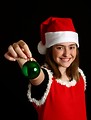Free Stock Photo: A cute young girl in a Santa hat holding a Christmas ornament