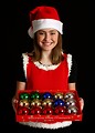 Free Stock Photo: A cute young girl in a Santa hat holding a box of ornaments
