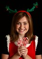 Free Stock Photo: A cute young girl in a Christmas outfit holding candy canes