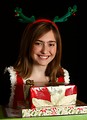 Free Stock Photo: A cute young girl in a Christmas outfit holding a stack of presents