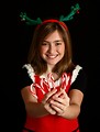 Free Stock Photo: A cute young girl in a Christmas outfit holding candy canes