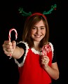Free Stock Photo: A cute young girl in a Christmas outfit holding candy canes