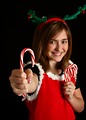Free Stock Photo: A cute young girl in a Christmas outfit holding candy canes