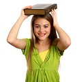 Free Stock Photo: A beautiful young girl holding a book on her head