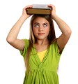 Free Stock Photo: A beautiful young girl holding a book on her head
