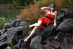 Free Stock Photo: A beautiful young woman posing in a red dress on rocks by a lake