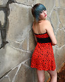 Free Stock Photo: A beautiful young woman posing in a red dress against a stone wall
