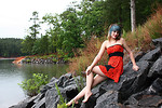 Free Stock Photo: A beautiful young woman posing in a red dress on rocks by a lake