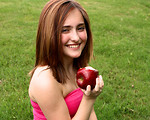 Free Stock Photo: A beautiful young girl holding an apple in the grass