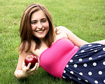 Free Stock Photo: A beautiful young girl holding an apple in the grass