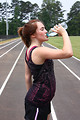 Free Stock Photo: A cute young girl drinking water on a track field