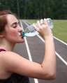 Free Stock Photo: A cute young girl drinking water on a track field