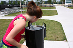 Free Stock Photo: A young girl drinking from a water fountain in a park