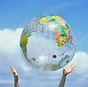 Free Stock Photo: Hands outstretched to catch an inflatable globe with a blue sky background.