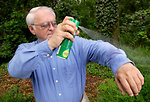 Free Stock Photo: A man spraying insect spray on his shirt