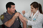 Free Stock Photo: A police officer receiving a vaccination shot from his doctor
